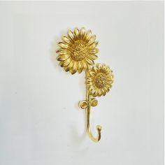 two sunflowers are attached to the handle of an iron hook on a white wall