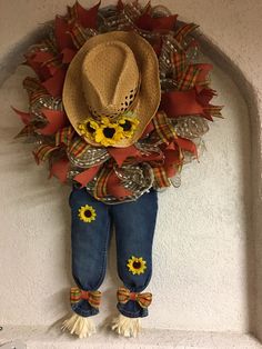 a scarecrow with sunflowers and a cowboy hat hanging on the wall in front of a doorway