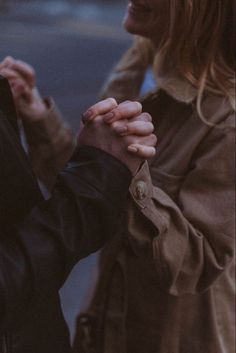 two people standing next to each other with their hands clasped in front of one another