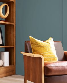 a brown leather chair sitting in front of a wooden book shelf with books on it