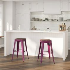 two purple stools in front of a white kitchen island with wooden floors and cabinets