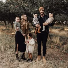 a man and woman with two children in an apple orchard