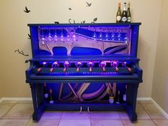 a piano with purple lights on it in front of a wall mounted clock and wine bottles