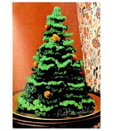 a cake shaped like a christmas tree sitting on a table next to a curtain and wall