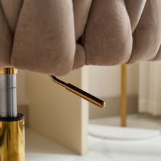 a close up of a gold and black object on a white table with a mirror in the background