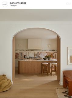 an archway leading into a kitchen with stools and counter tops on either side of the room