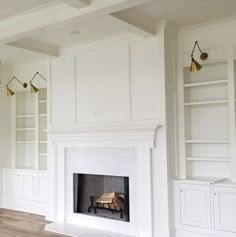 an empty living room with white walls and wood flooring, built in bookcases