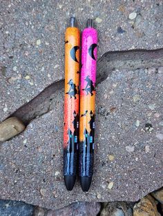 two pens sitting on top of a rock covered ground next to another pen with halloween designs