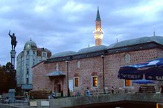 an old brick building with a clock tower in the background and people walking around it