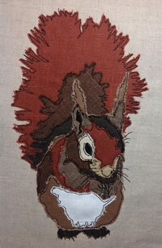 an embroidered squirrel is shown on a piece of cloth