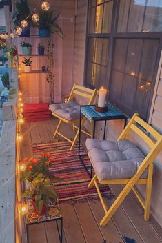 two yellow chairs sitting on top of a wooden deck next to a table with candles