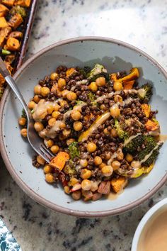 a white bowl filled with food next to a spoon