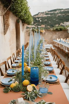 a long table is set with blue candles and plates