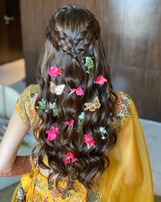 the back of a woman's head with flowers in her hair and butterfly clips