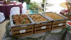 three trays filled with food sitting on top of a table covered in white cloth