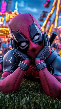 deadpool is laying in the grass at an amusement park