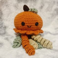 an orange crocheted stuffed animal sitting on top of a white blanket