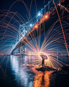 a man standing in front of a bridge with lots of sparks