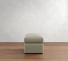 a footstool sitting on top of a wooden floor next to a white wall