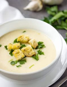 a white bowl filled with soup and garnished with parsley on the side