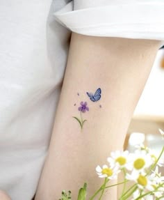 a woman with a tattoo on her arm holding a bouquet of daisies and a butterfly