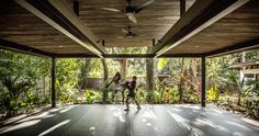 two people are dancing in the middle of an outdoor area with trees and plants on either side