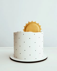 a white cake with black dots and a sun decoration on top