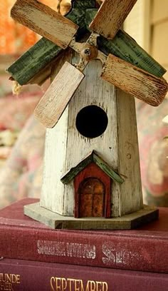 a wooden birdhouse with a windmill on top