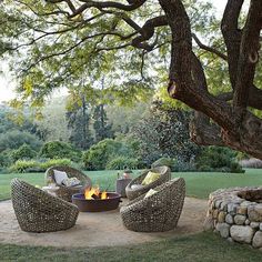 an outdoor fire pit surrounded by wicker chairs