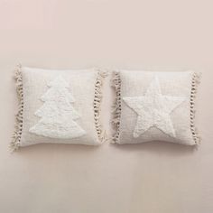 two white pillows with stars and fringe trims on them, one has a christmas tree in the middle