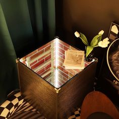 a table with a glass box and flowers on it next to a black and white checkered chair