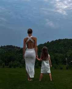 a mother and daughter walking in the grass