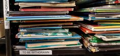 a stack of books sitting on top of a shelf next to a pile of papers