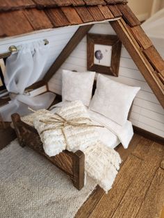 a doll house bed with white pillows and blankets