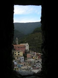 an open window with a view of a town in the distance and mountains behind it