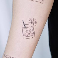 a tattoo on the arm of a woman with a drink and ice cubes in it