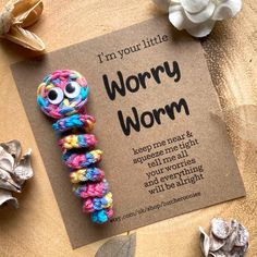 a very cute little worm made out of yarn and some flowers on a table with a sign that says, i'm your little worry wormy wormy worm