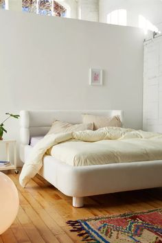 a white bed sitting on top of a wooden floor