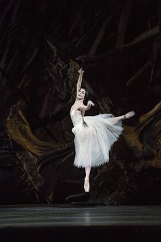 ballerina in white tutu on stage with arms outstretched to the side and head turned backwards