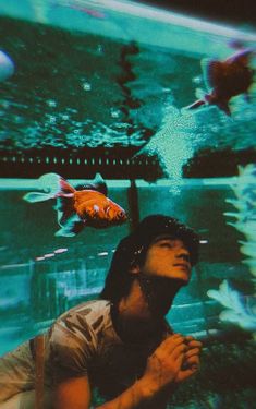 a woman looking up at fish in an aquarium