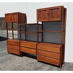 three wooden shelves with drawers and cupboards