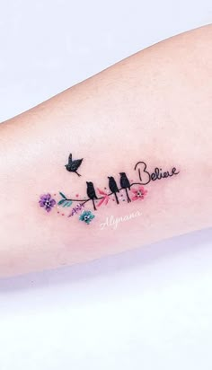 a small tattoo with birds and flowers on the arm