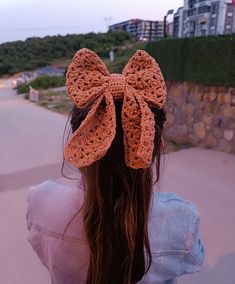 a woman with long hair wearing a crocheted bow