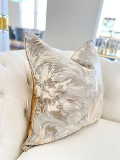 a close up of a white couch with a decorative pillow on it's back