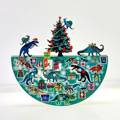 a christmas tree is decorated with dinosaurs and other holiday decorations on a green platter