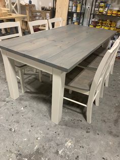 a wooden table and chairs in a room with other items on the shelves behind it