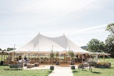 a large tent set up with tables and chairs for an outdoor wedding reception in the countryside