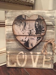 a wooden frame with an image of two people and a baby in the shape of a heart