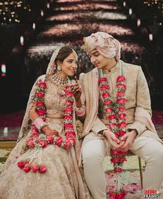 two people sitting next to each other on a bench with flowers in front of them