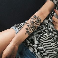 a woman with a flower tattoo on her arm holding a cell phone in her hand